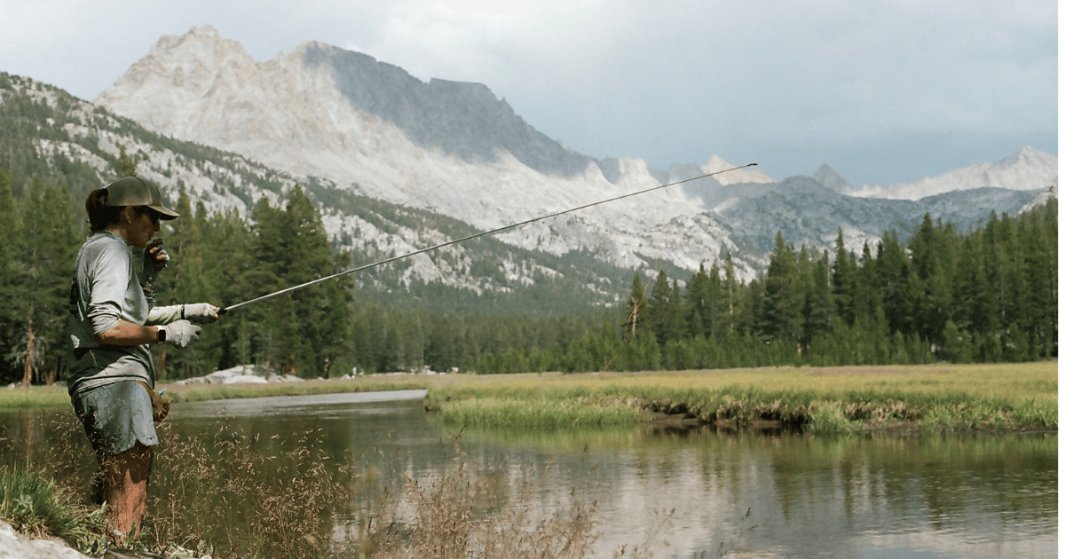 Young woman fly-fishing while standing in Owens River against