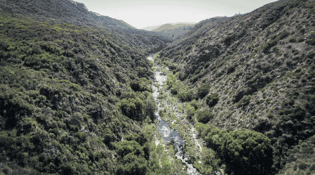 A stream flows in a canyon of scrubby hills