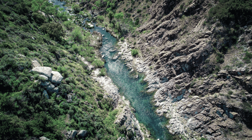 A top down view of a bright turquoise river with rocks around it